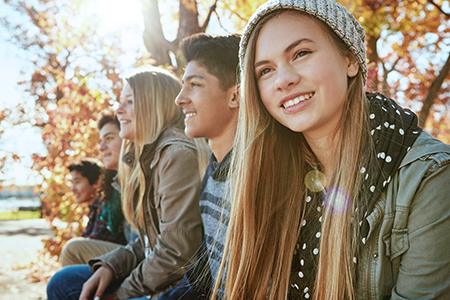 Teenagers in a row sitting outside
